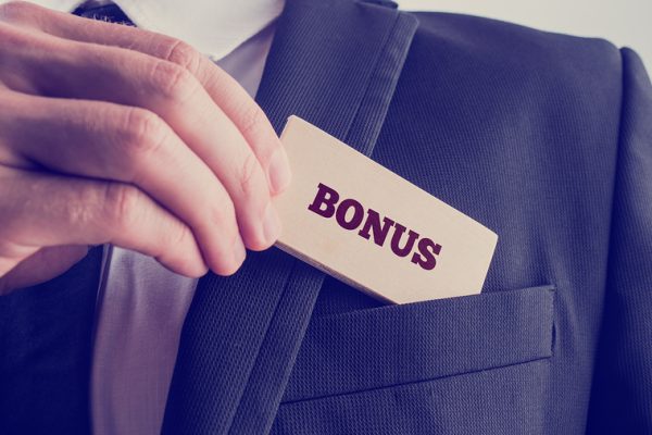 Close up Businessman in Black Suit Putting Small Wooden Piece with Bonus Text to Front Pocket. A Simple Company Bonus Concept.