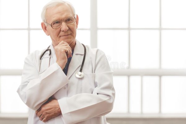 handsome-old-doctor-pensive-white-medical-coat-eyeglasses-looking-away-smiling-standing-against-window-79702088